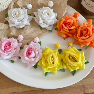 Detailed macro view of large silk rose earrings in white orange pink and yellow
