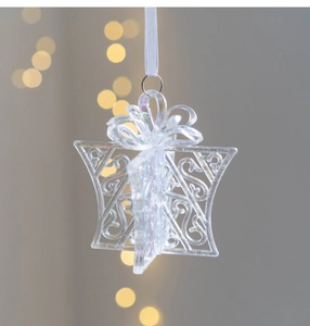 Close-up of a clear iridescent Christmas star ornament with a white ribbon and bokeh lighting