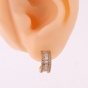 Macro shot of gold-finished C-shaped earrings with micro-pave crystals on a model