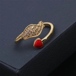 Détail d'une bague ajustable avec aile en zircons et cœur rouge sur support noir