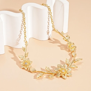 Detailed close-up of golden floral necklace with sparkling crystals on beige background