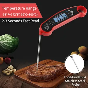 Digital meat thermometer with folding probe measuring steak on a wooden board
