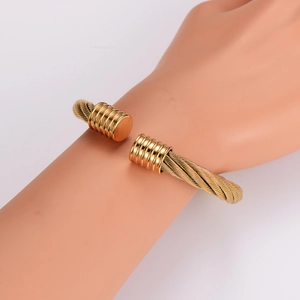 Detail view of gold cable wire open cuff bracelet with woven texture on model arm
