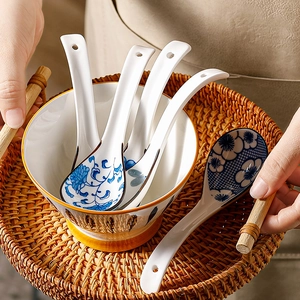 Japanese ceramic soup spoon set with blue floral patterns on a woven tray