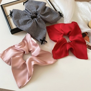 Close-up of silk oversized scrunchies in red and pink with subtle bow details