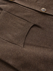 Close-up of a brown knit cardigan with ribbed pocket and amber textured button
