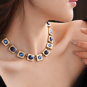 Detail einer Vintage-Goldhalskette mit quadratischen Gliedern und blauen Katzenaugen