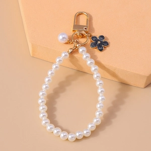 Detail of beaded pearl keychain featuring a dark floral charm and gold metal clasp