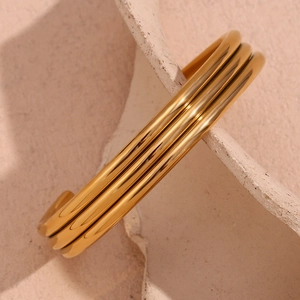 Detailed close-up of a three-layer open bangle in polished 18K gold-plated stainless steel
