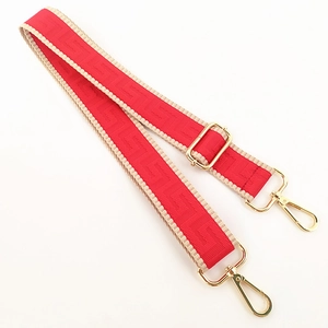 Detail of adjustable red woven canvas bag strap with golden metal hooks and buckles