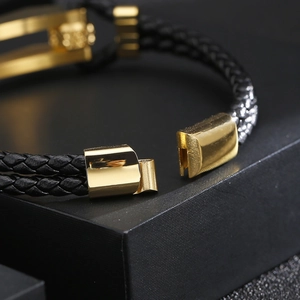 Macro shot of gold magnetic clasp on black woven leather bracelet in premium gift box