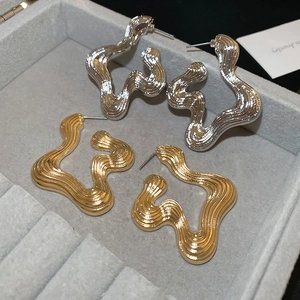 Irregular geometric wavy textured earrings in gold and silver finish on velvet display