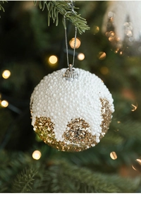 Vue détaillée d'une boule de Noël avec neige en mousse blanche et paillettes dorées