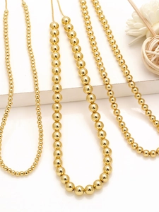 Detail view of graduated 18k gold plated beaded necklaces on white display stand