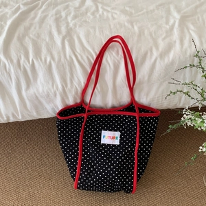 Black polka dot canvas tote bag with red trim and FUTURE patch in a cozy home setting