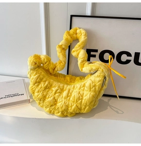 Detail of soft yellow pleated cloud bag texture on minimalist shelf with art background