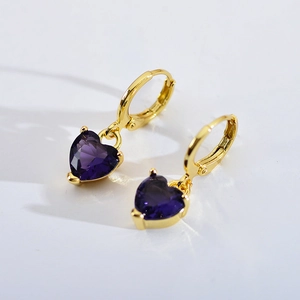 Detail of gold hoops with purple heart-shaped zircon stones on a white background
