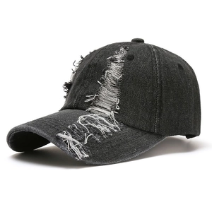 Detail shot of distressed dark denim baseball cap showing vintage frayed hole texture