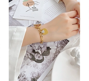 Détail de breloques cœur en or 18K sur bracelet à maillons avec zircons étincelants