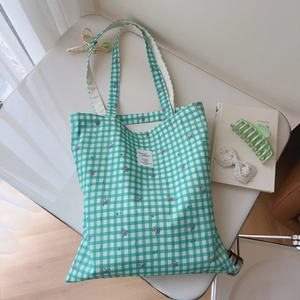 Detailed view of green checkered tote bag with floral embroidery and Animal Patterns patch