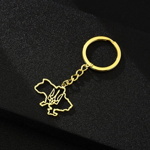 Detail of golden stainless steel Ukraine map keychain with trident emblem on dark background