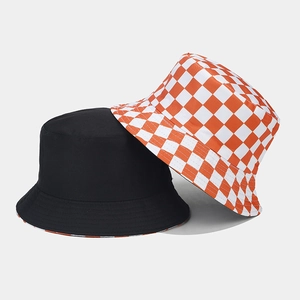 Close-up of stacked cotton bucket hats in solid black and orange checkerboard pattern