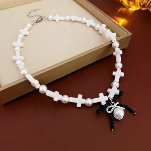 Cross pearl necklace featuring a black beaded bow pendant with metal extension chain