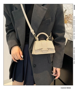 Sac bandoulière beige tressé porté avec un blazer gris et une poignée supérieure