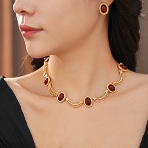 Close-up of a vintage golden jewelry set with red oval gemstones on a model's neck