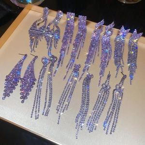 Macro detail of silver geometric rhinestone tassel earrings and purple diamond heart studs