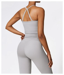Detail view of grey yoga top with cross back design and high waist leggings on model