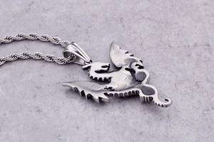 Detail of a stainless steel dragon pendant with engraved text on a twisted rope chain