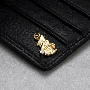 Macro view of a gold rabbit charm with a clear cubic zirconia on black leather