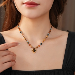Close-up of bohemian heart stone pendant necklace with brown and blue beaded chain
