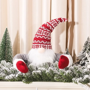Christmas gnome topper with red knitted hat and white beard on snowy pine branch decor