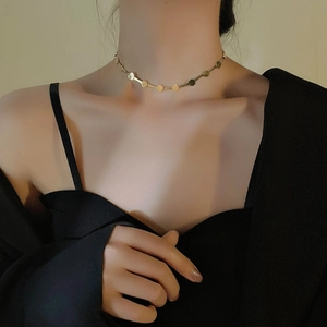 Detailansicht einer goldenen Choker-Halskette mit flachen runden Pailletten am Schlüsselbein