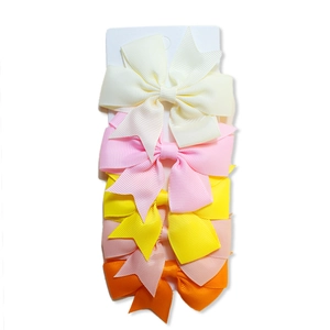 Close-up of five solid color ribbed ribbon fishtail bow hair clips on display card