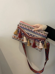 Close-up of bohemian woven crossbody bag with colorful tassels and embroidery strap