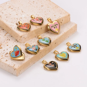 Pendentifs cœurs en émail coloré et acier inoxydable doré sur un socle en pierre beige