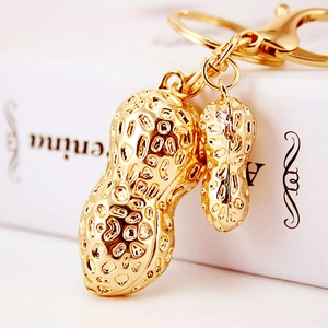 Golden cat eye stone peanut pendant keychain with double charms on a book background