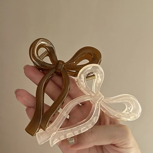 Close-up of brown and cream ribbon bow claw clips with glossy finish and gold metal spring