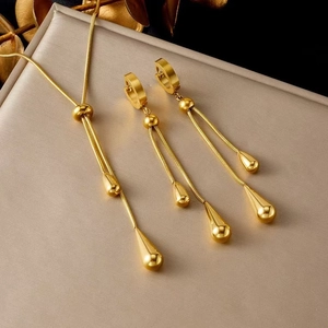 Makroaufnahme von goldenem Tropfen-Schmuckset auf gebürsteter Metalloberfläche mit Glanz