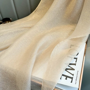 Detail of beige silk scarf fabric with elegant gold glitter texture and soft folds