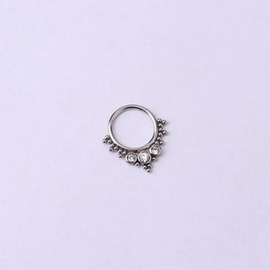 Détail macro d'un anneau de nez 16G en acier argenté avec perles et zircons clairs
