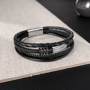 Detail of multi-layer black braided leather bracelet with silver magnetic clasp