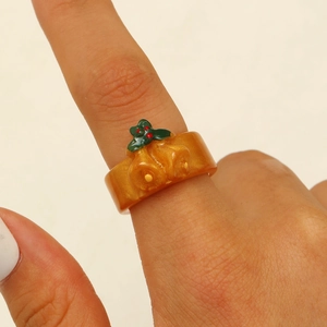 Detail of an orange Christmas bell ring featuring green leaves and red berries
