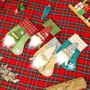 Set of four burlap Christmas gnome stockings with HO HO HO signs on festive tablecloth