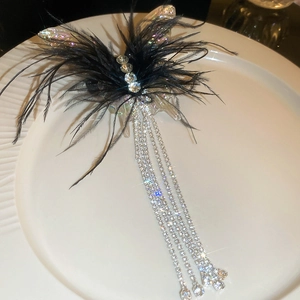 Macro detail of butterfly hair clip with black feathers and shimmering rhinestone tassels