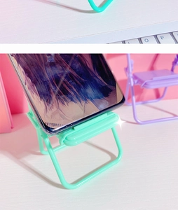 Close-up of mint green mini folding chair phone stand showing practical desktop usage