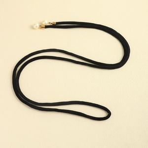 Detail of elegant black velvet rope belt with white pearl beads and gold metal tips